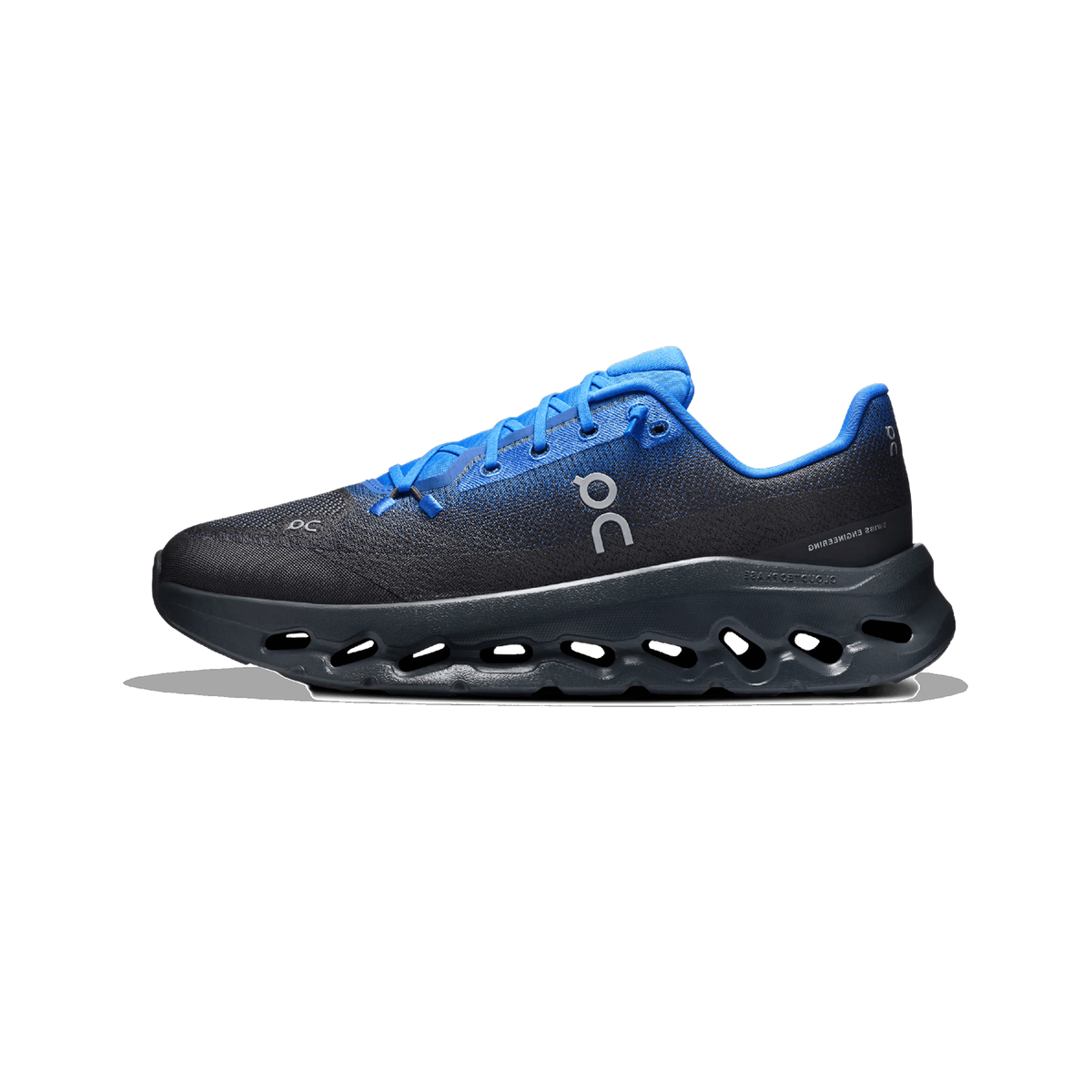 Lateral view of an On Running Cloudtilt sneaker in black and blue with a cutout CloudTec sole and blue laces.