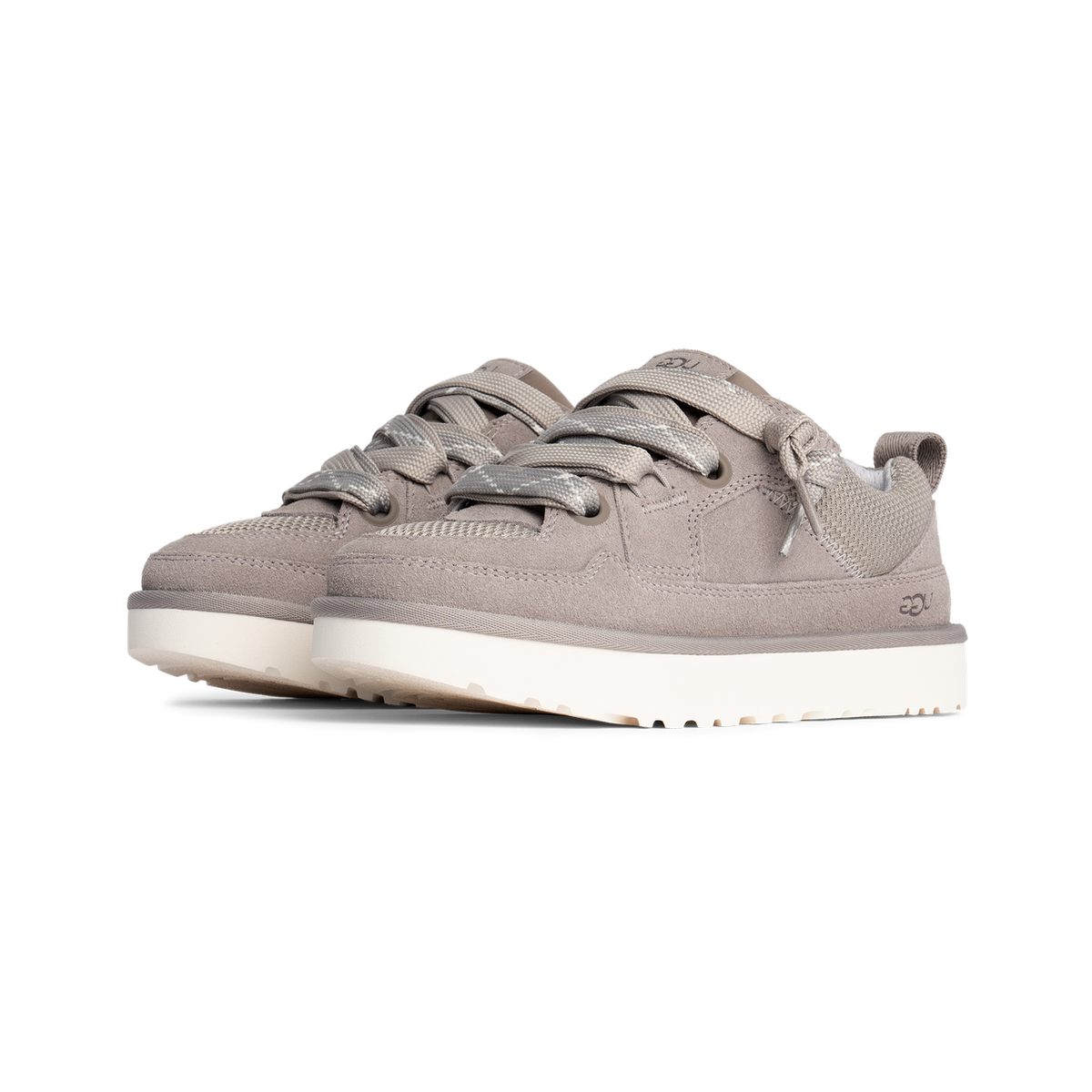 Pair of grey suede UGG low-top sneakers with thick fabric laces and white chunky soles, angled toward the left.