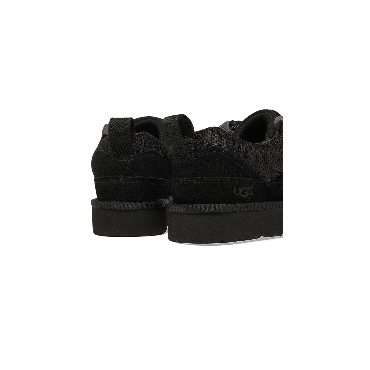 Close-up rear view of a pair of black UGG Lowmel Lo sneakers showing the heel counters, pull tabs, and UGG logo embossed on the suede heel.