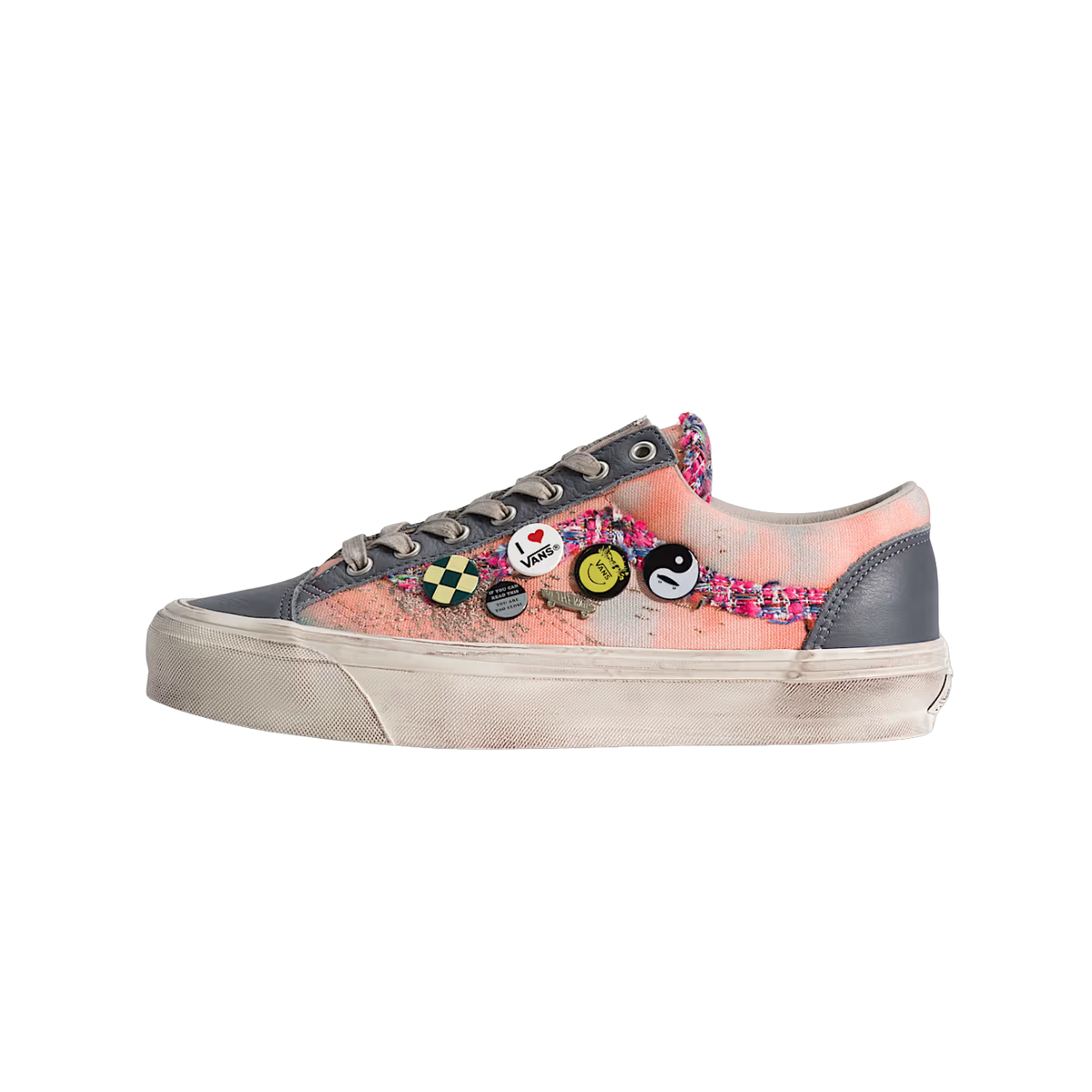 Side view of a Vans Old Skool 36 LX sneaker with distressed gray leather panels, pink and white tie-dye canvas, a woven pink and blue fabric strip, pin badges including Vans and yin-yang designs, and an aged off-white sole.