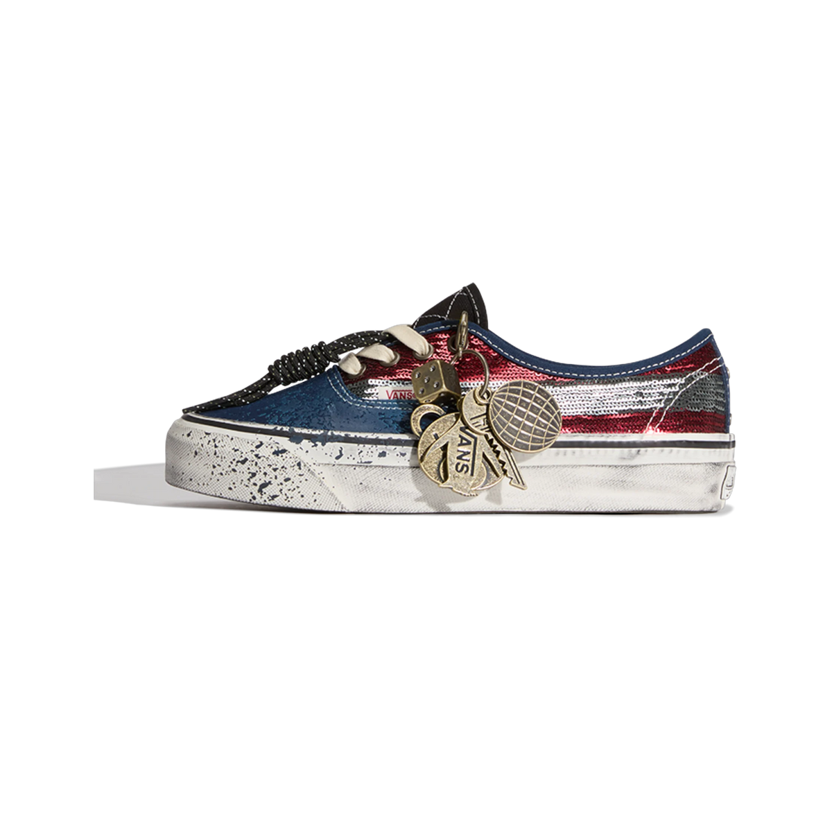 Side view of a Vans Authentic sneaker with sequined red and silver striped upper, navy toe and heel, distressed white sole, and gold charm keychain hanging from the laces.