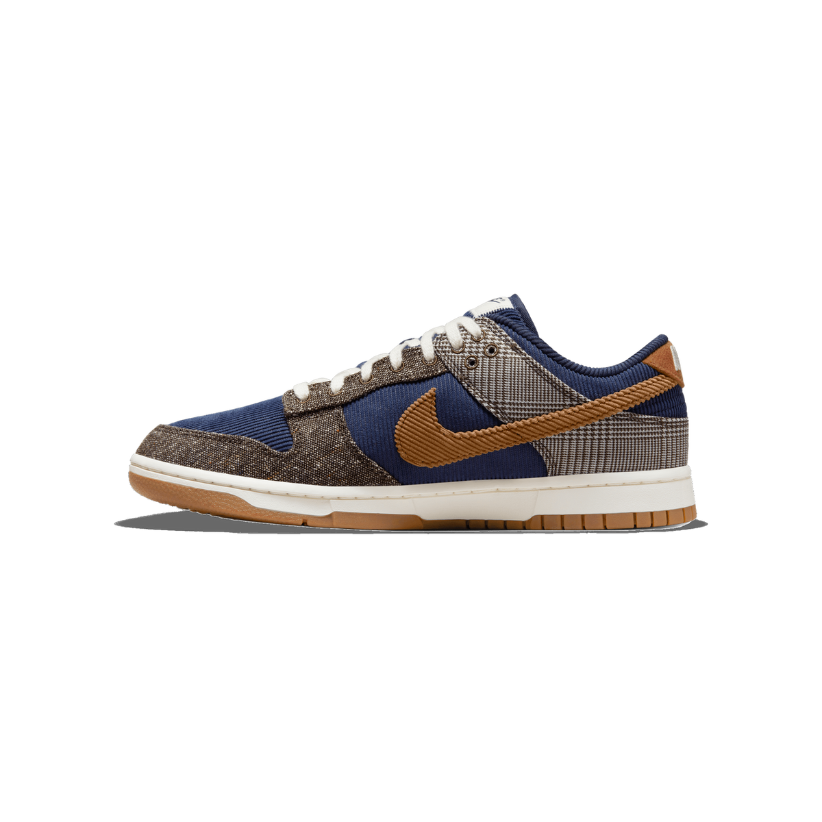 Seitenansicht eines Nike Dunk Low Sneakers mit marineblauen Cordpaneelen, hellbraunem Wildleder-Swoosh, braunen Tweed-Akzenten an Zehe und Ferse, grauen Hahnentritt-Details und einer Gum-Gummisohle.