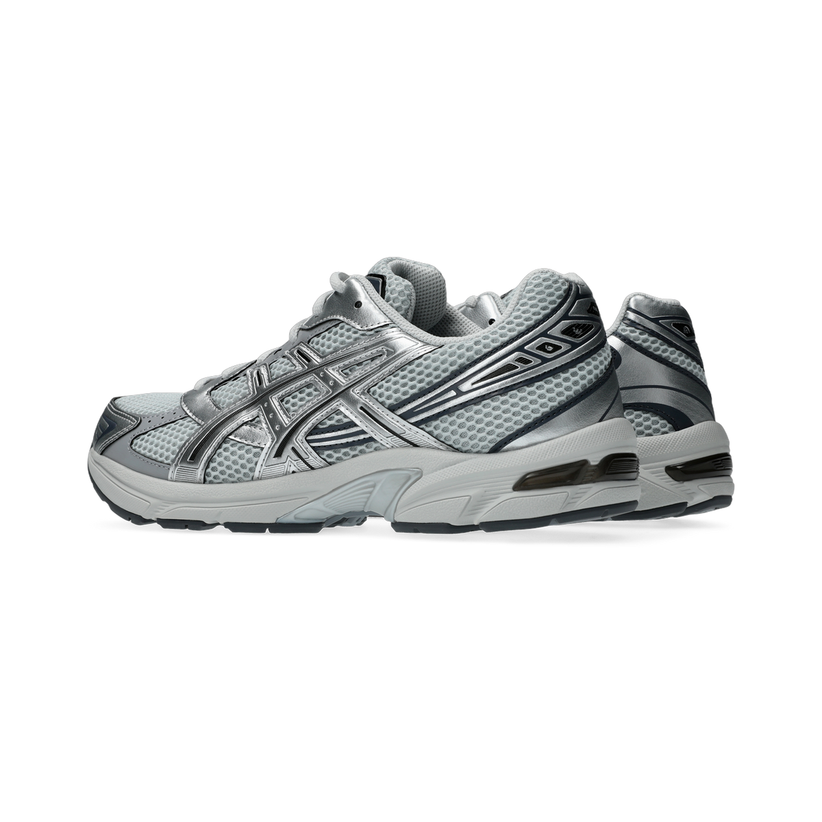 Side view of a gray and silver Asics Gel-1130 sneaker with mesh upper and chunky white midsole, paired with a second shoe visible behind it.