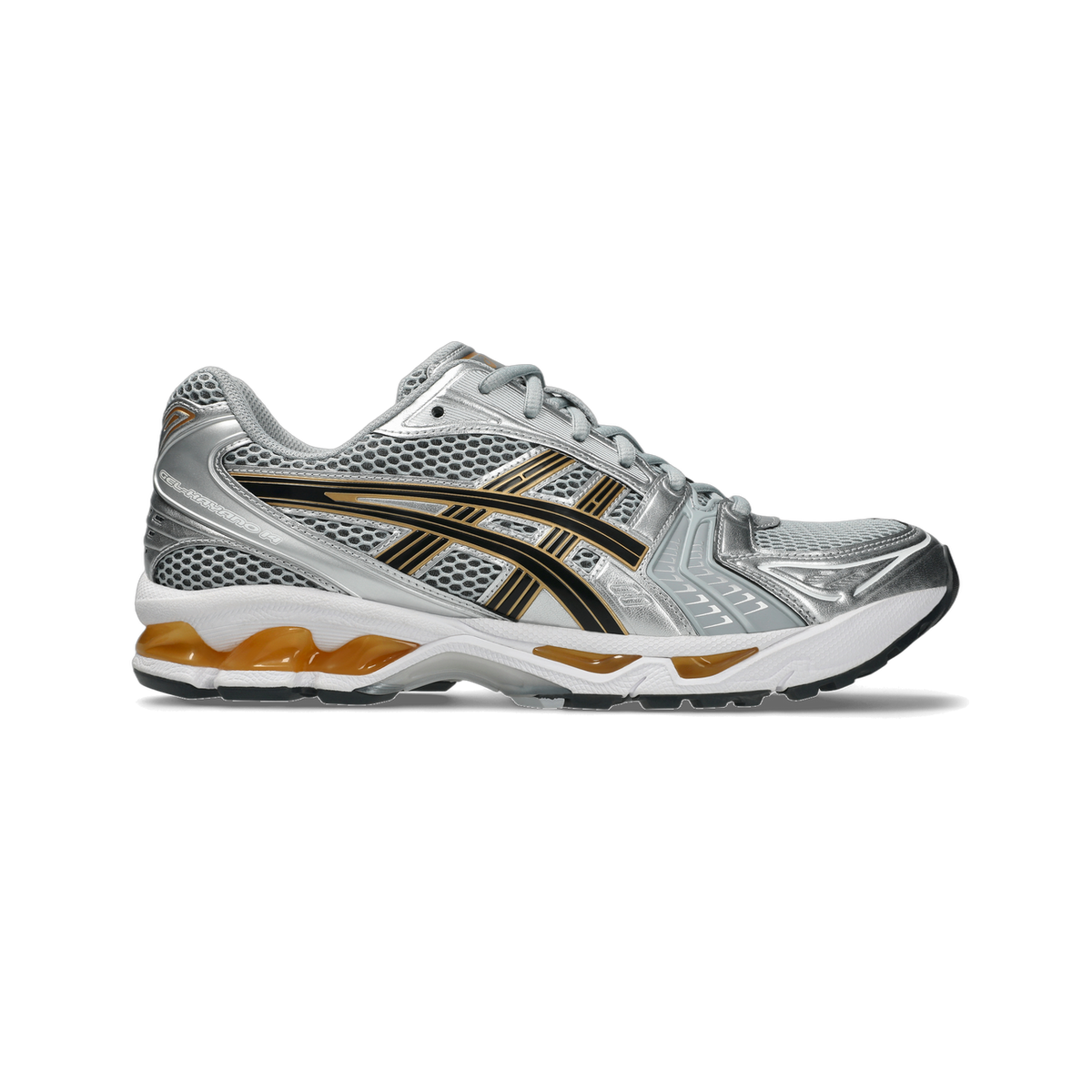 Side view of a silver Asics Gel-Kayano 14 running shoe with black and gold stripe overlays and an orange gel unit visible in the heel