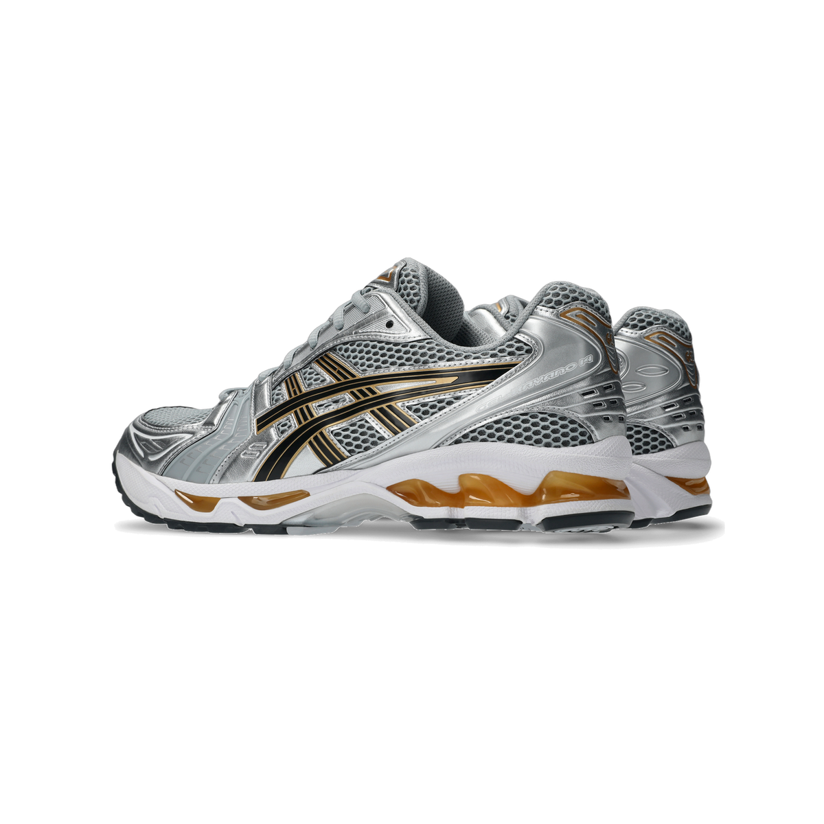Side view of a pair of silver Asics Gel-Kayano 14 sneakers with black stripe overlays and gold accents on a white midsole, angled toward the left.