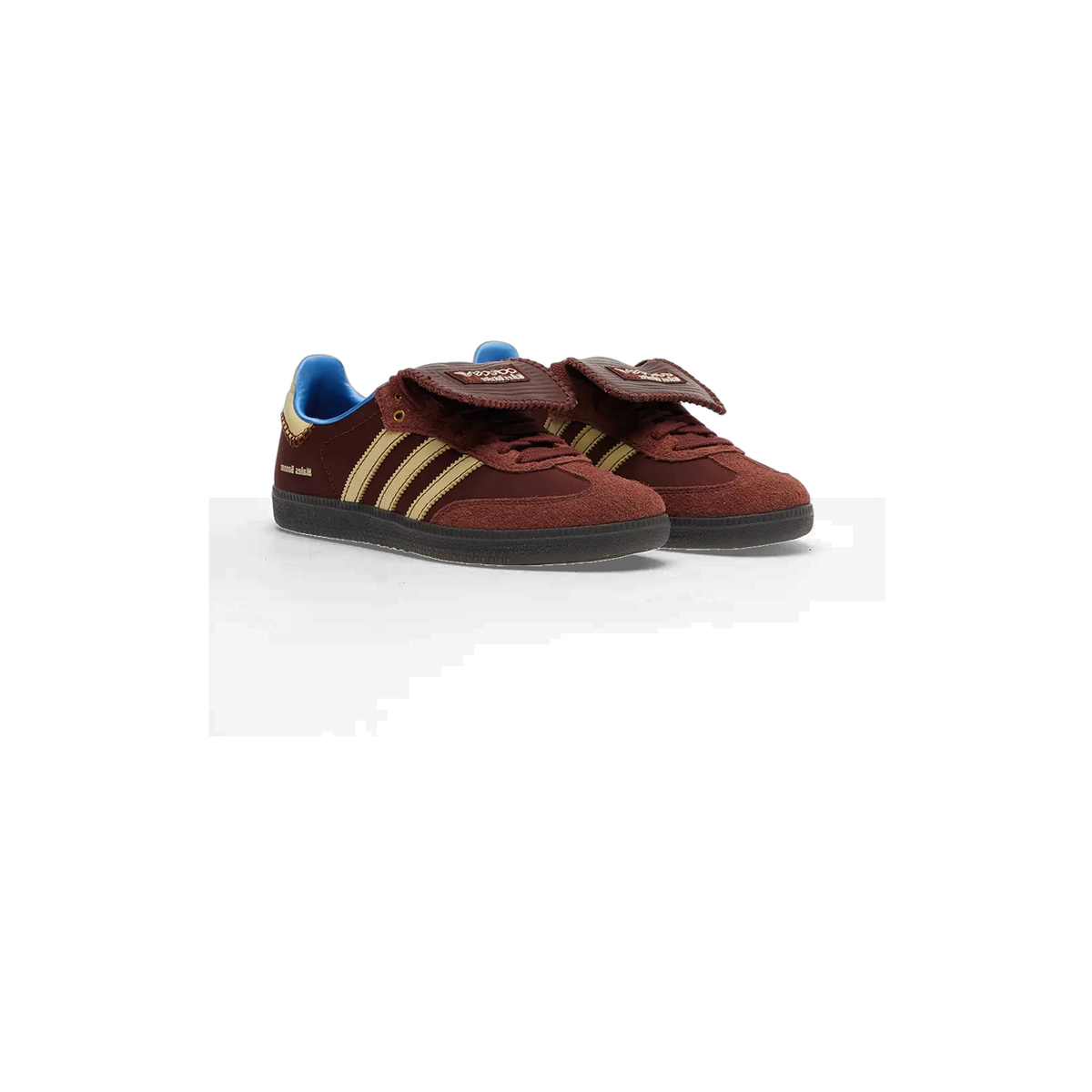 Pair of brown Adidas Samba Wales Bonner sneakers with gold stripes, flap-style tongues, blue heel tabs, and black soles, angled toward the left.