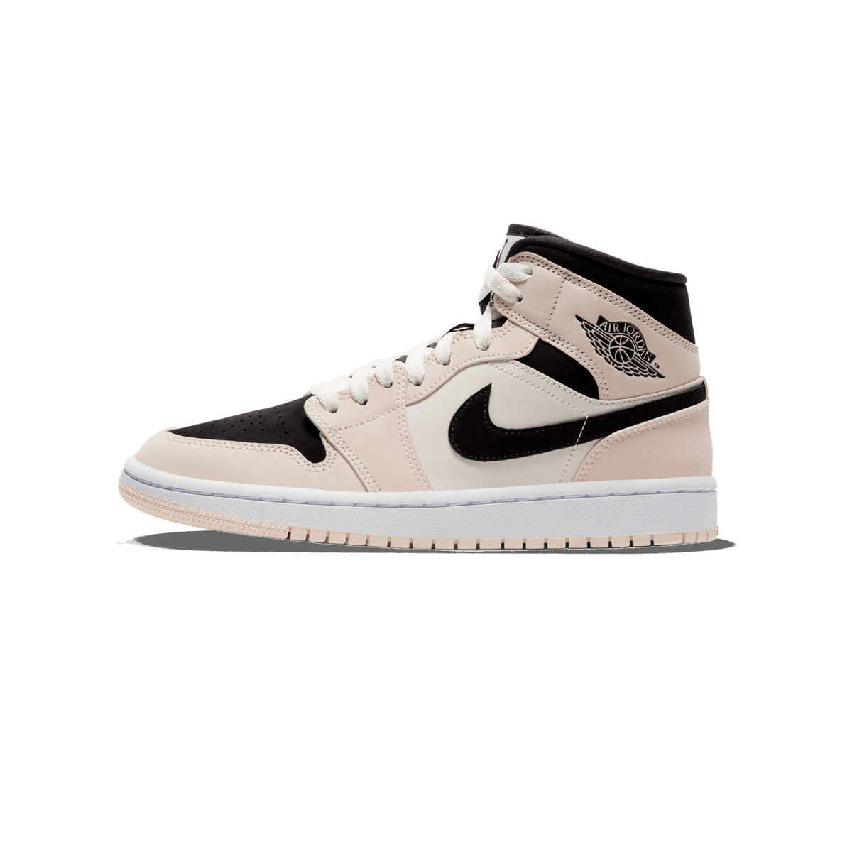 Side profile of a single high-top Air Jordan 1 Mid sneaker with the toe pointing left, showing a pale peach-beige leather upper, black overlays on the toe and collar, a black Nike Swoosh, an Air Jordan Wings logo on the ankle, white laces, and a whit
