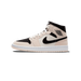 Side profile of a single high-top Air Jordan 1 Mid sneaker with the toe pointing left, showing a pale peach-beige leather upper, black overlays on the toe and collar, a black Nike Swoosh, an Air Jordan Wings logo on the ankle, white laces, and a whit