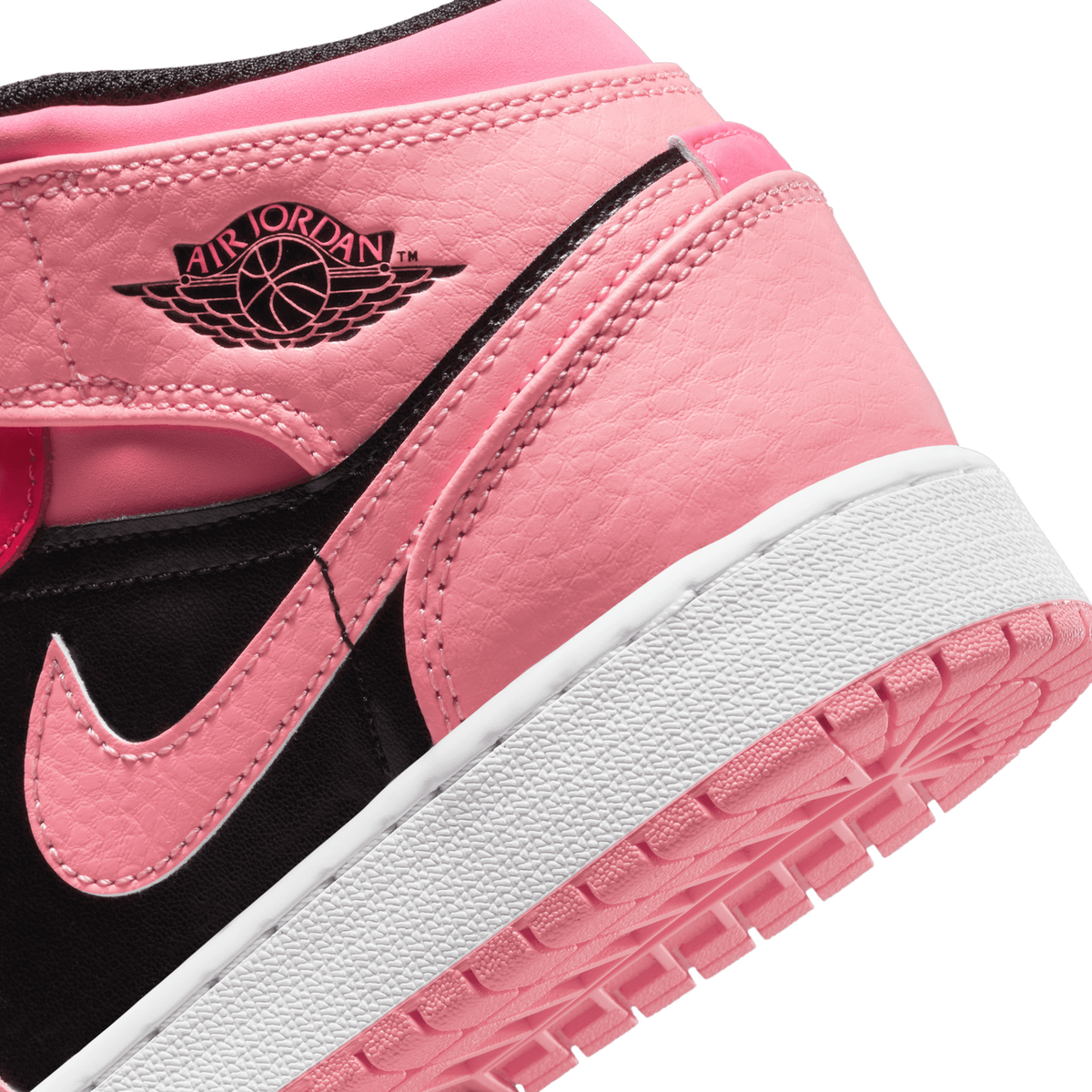 Close-up angled view of a pink and black Air Jordan 1 Mid showing the Wings logo, Swoosh, and white midsole with pink outsole