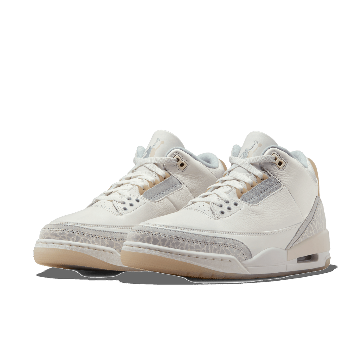Front-angled view of a pair of white Air Jordan 3 Retro Craft Ivory sneakers with grey suede accents, elephant print detailing, and tan rubber soles.