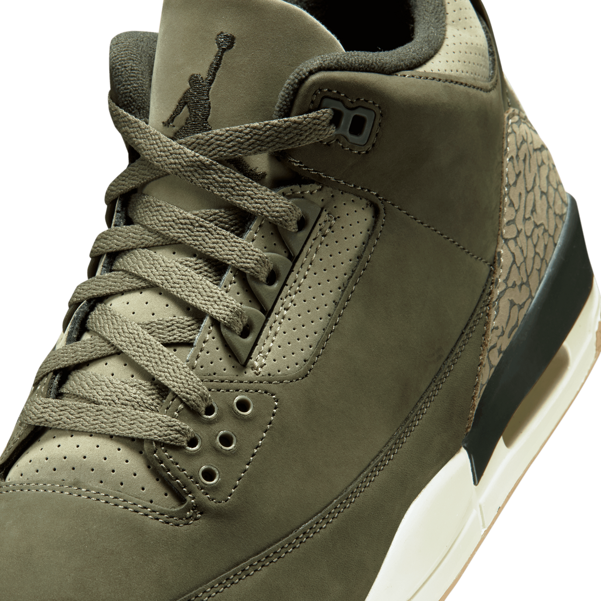 Close-up angled view of an olive-green Air Jordan 3 showing the Jumpman logo on the tongue, laces, perforated eyestay, and elephant print detailing on the heel.