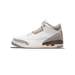 Side view of a white leather Air Jordan 3 sneaker with grey suede overlays on toe, heel, and tongue, brown mudguard, and tan laces and midsole, toe pointing left
