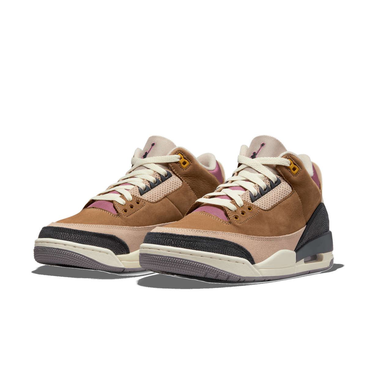 A pair of brown, beige, and black Air Jordan 3 sneakers shown side by side at a three-quarter angle, with pink accents visible inside the collars and cream laces.