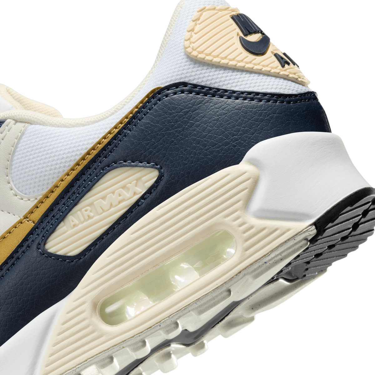 Close-up angled view of a Nike Air Max 90 showing the visible air unit, navy leather overlay, cream midsole with Air Max branding, and swoosh logo on the heel