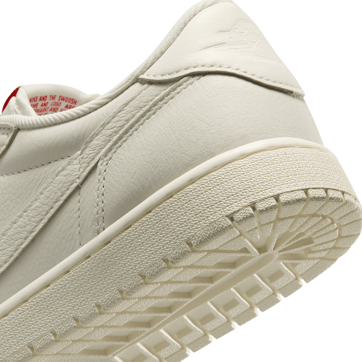 Close-up angled view of a white Jordan 1 Retro Low OG Sail showing the heel, sole tread, and inner tag with red text.