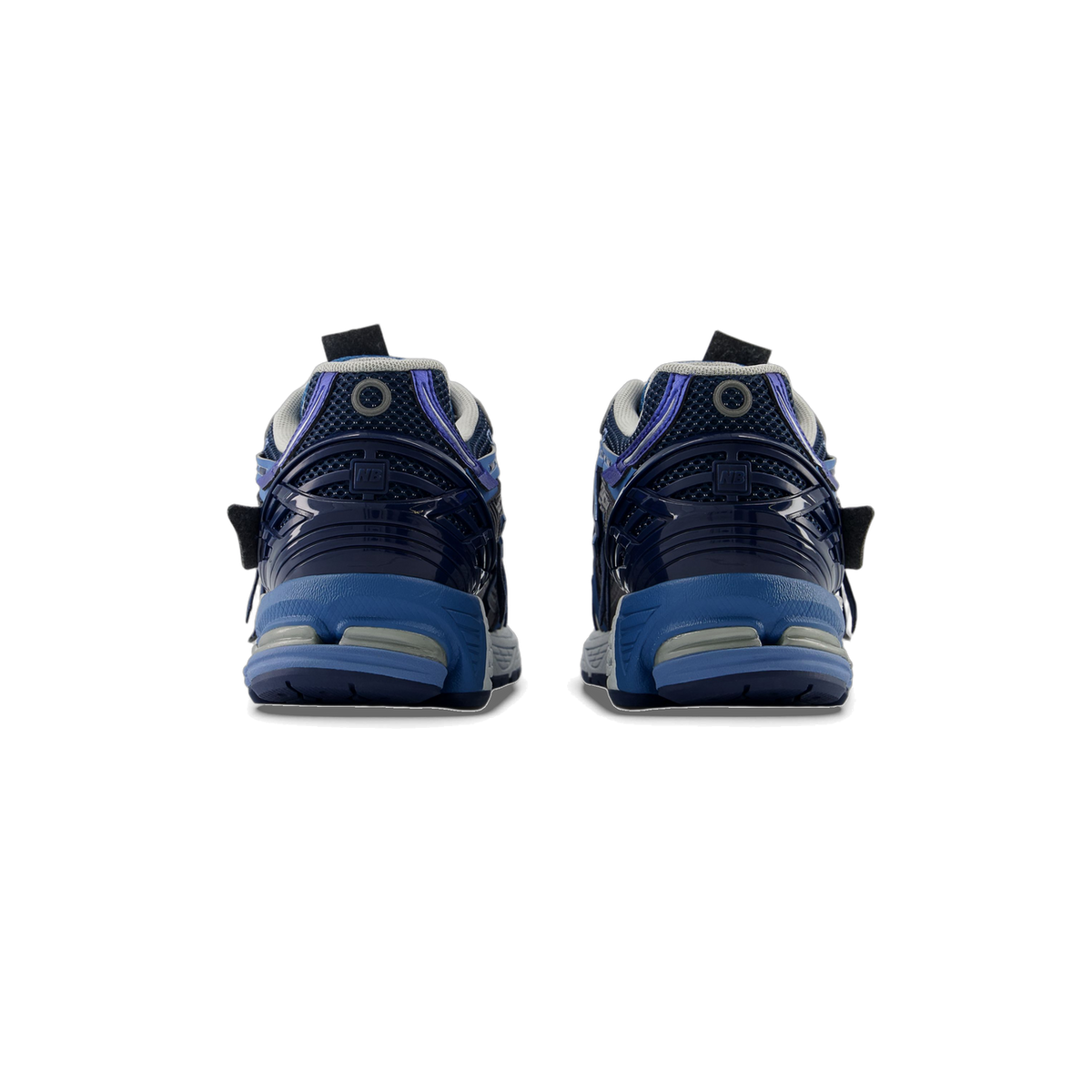 Rear view of a pair of navy and blue New Balance 1906A sneakers showing the heel panels with NB logo and blue midsoles