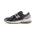 Side view of a navy New Balance 1906R sneaker with silver N logo, white midsole, and black outsole, toe pointing left.