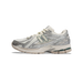 Side view of a New Balance 1906R sneaker in white and silver metallic mesh with a cream and green N logo and off-white midsole with dark green accents on the outsole.