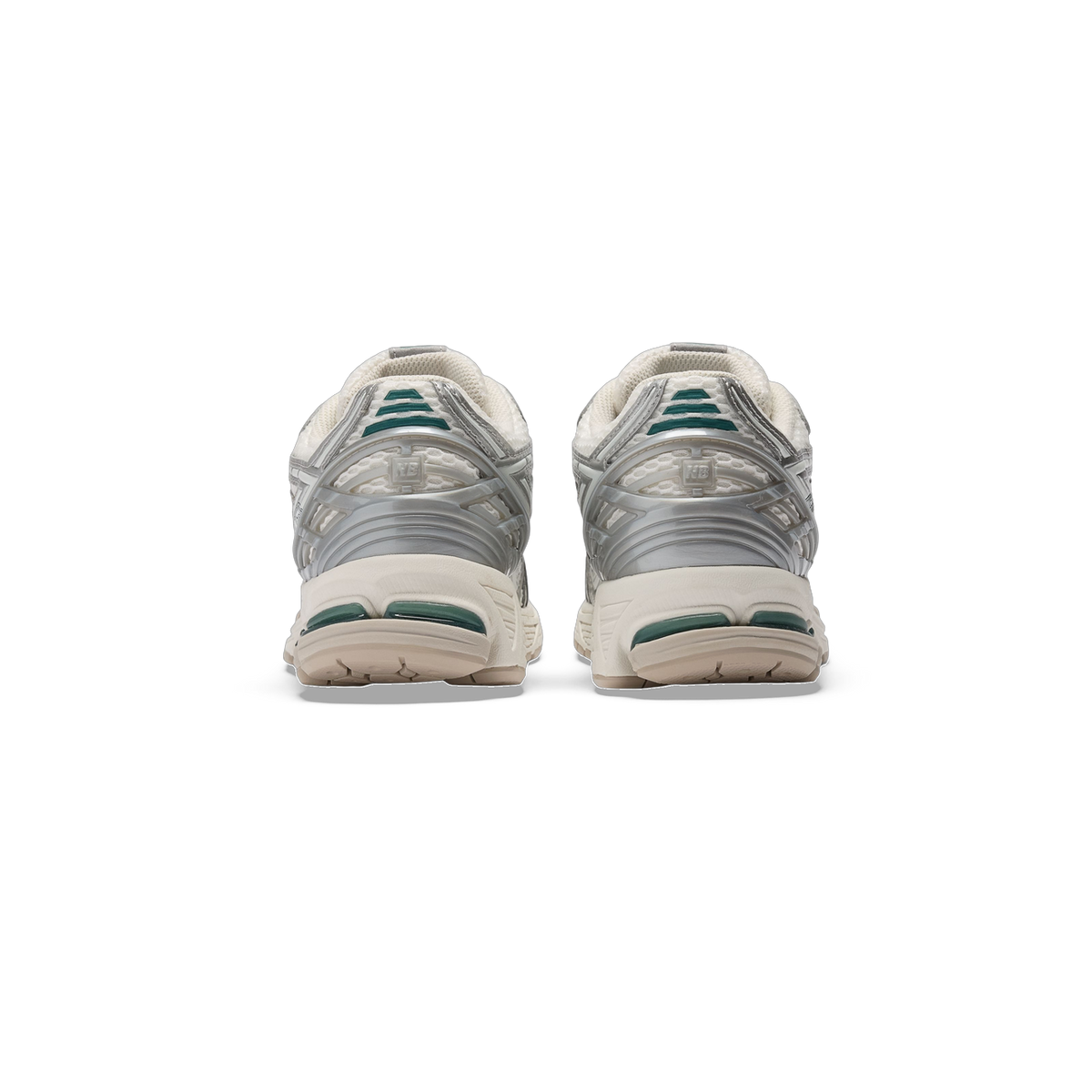 Rear view of a pair of New Balance 1906R sneakers in white and silver with green heel accents and cream midsoles.