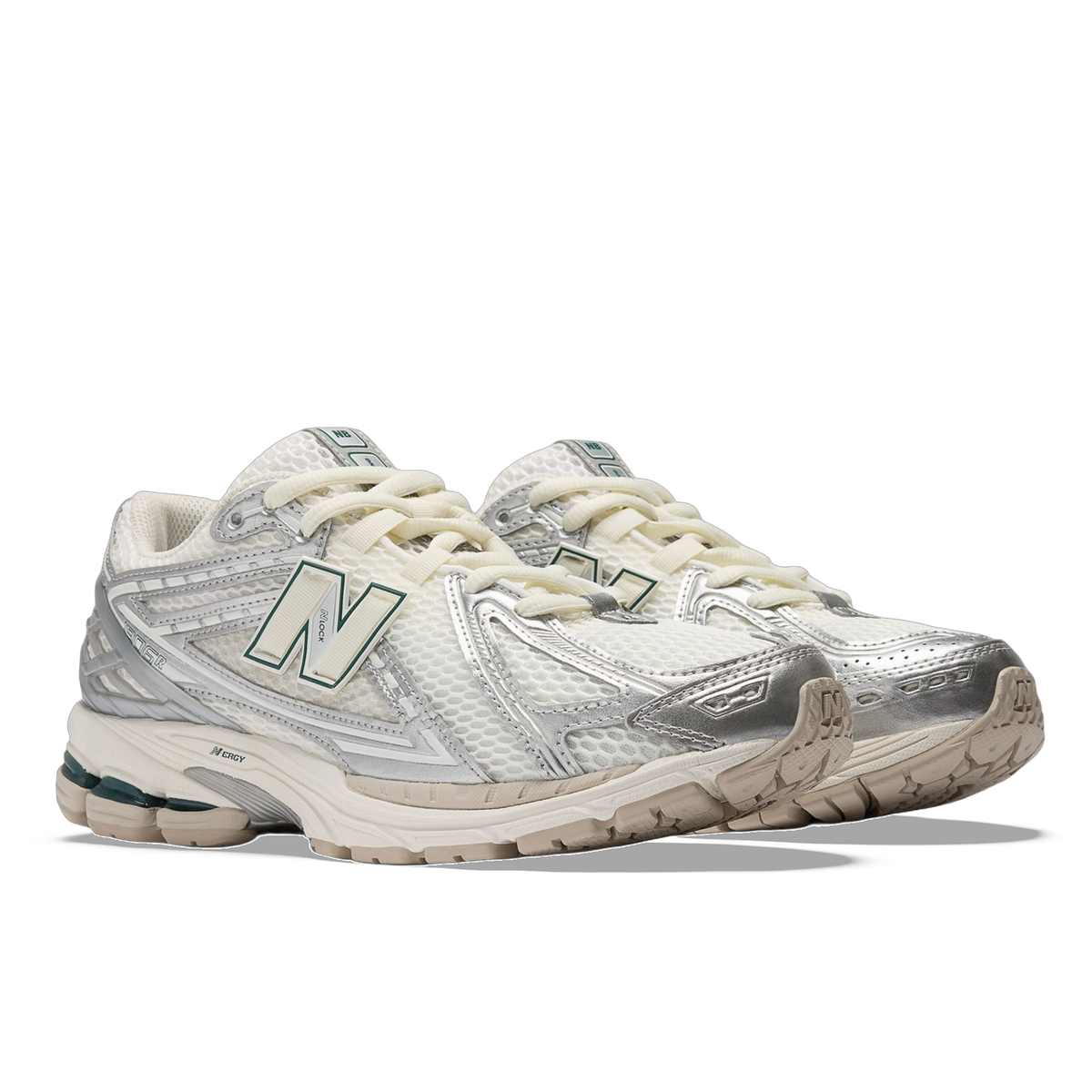 Pair of New Balance 1906R sneakers in white mesh with metallic silver overlays, cream laces, green N logo, and tan outsoles, shown from the front side angle.