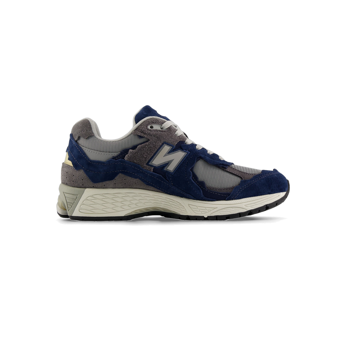 Side view of a navy and gray New Balance 2002R sneaker with suede and mesh panels, a gray N logo, and an off-white midsole with visible lugs.