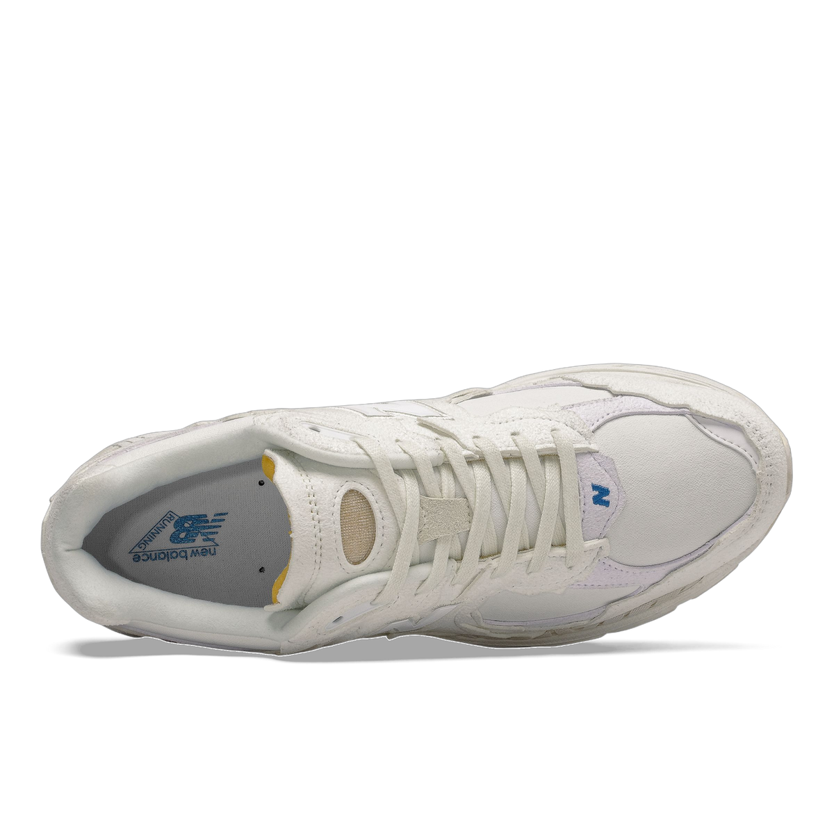 Top-down view of a white New Balance 2002R sneaker with tongue folded down revealing a grey insole with New Balance logo and yellow accent lining