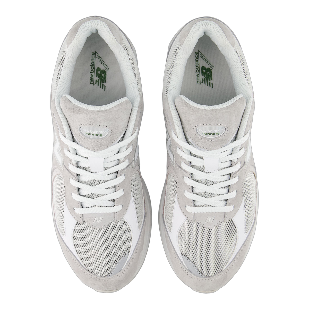 Top-down view of a pair of gray and white New Balance 2002R sneakers with white laces and green branding visible on the gray tongue labels