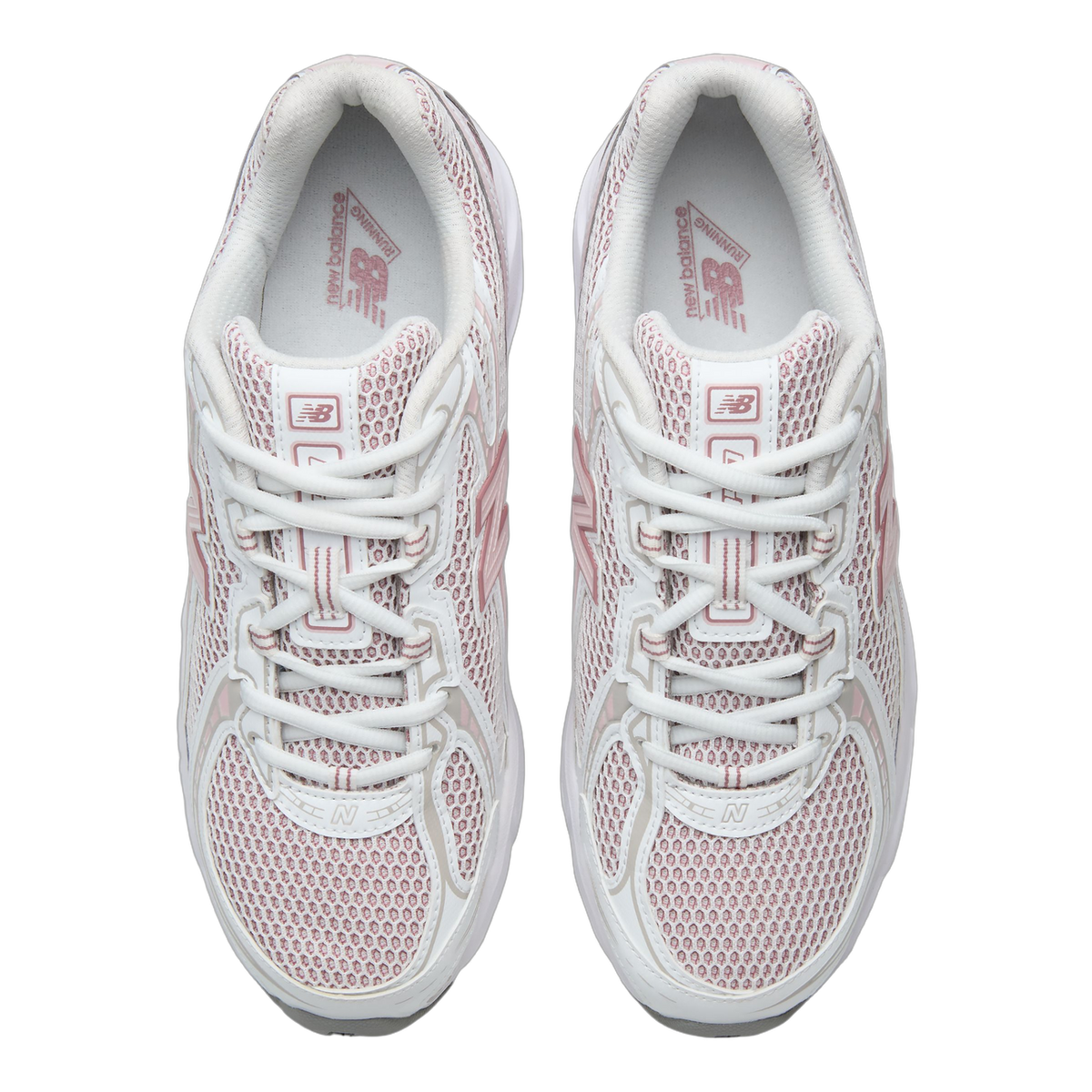 Top-down view of a pair of white mesh sneakers with pink overlays, pink New Balance branding on the tongue, and pink logo print on the insoles.