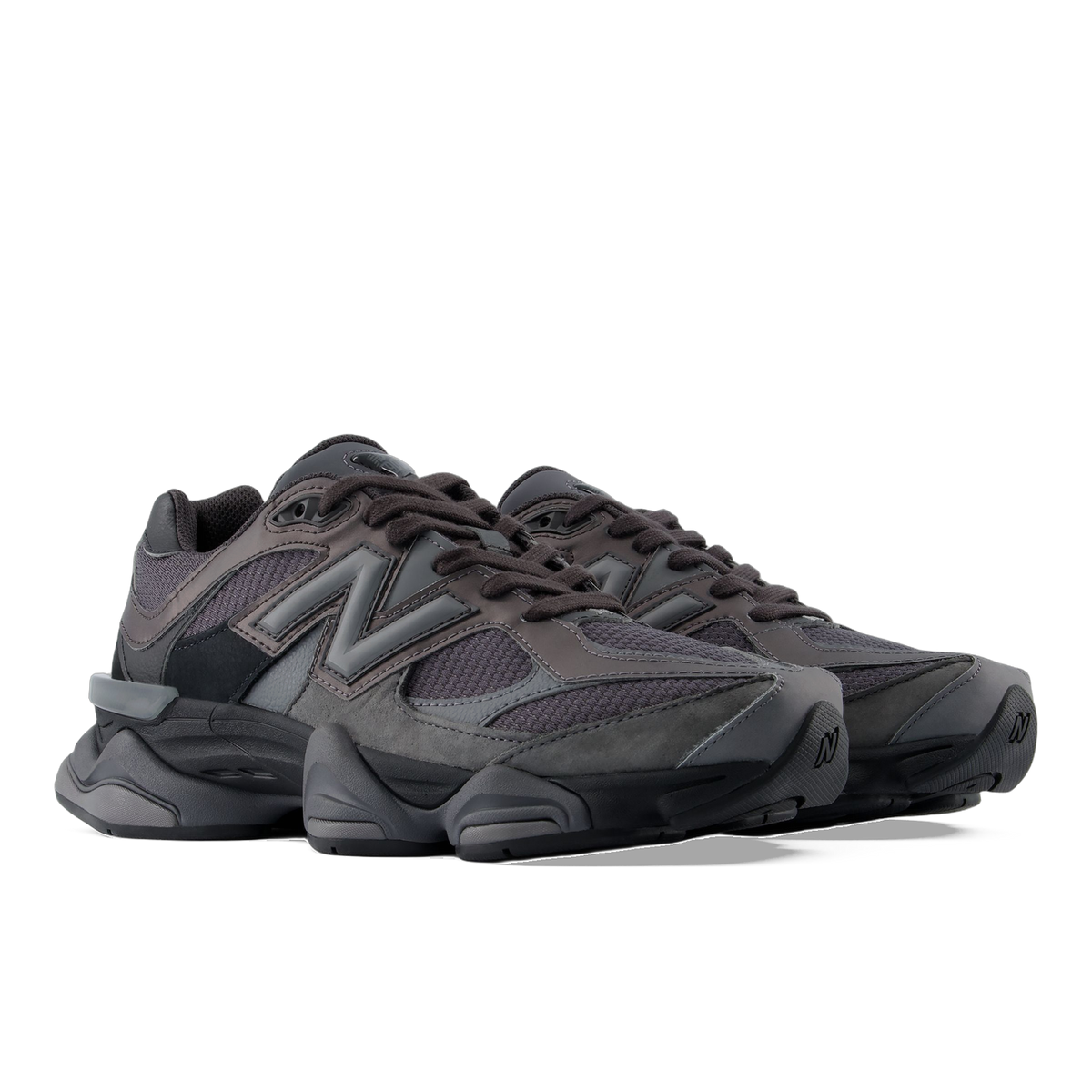 Front-angled view of a pair of black and grey New Balance 9060 sneakers with chunky soles and grey N logo on the sides.