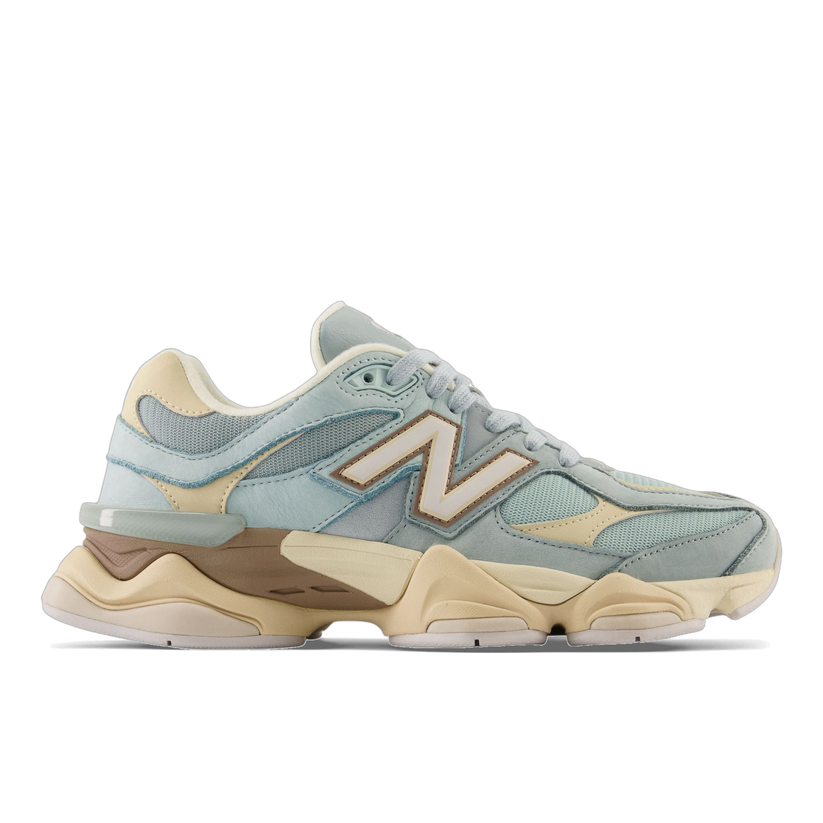 Side view of a left New Balance 9060 sneaker in light blue-gray suede and mesh with a tan chunky midsole and cream N logo, toe pointing left.