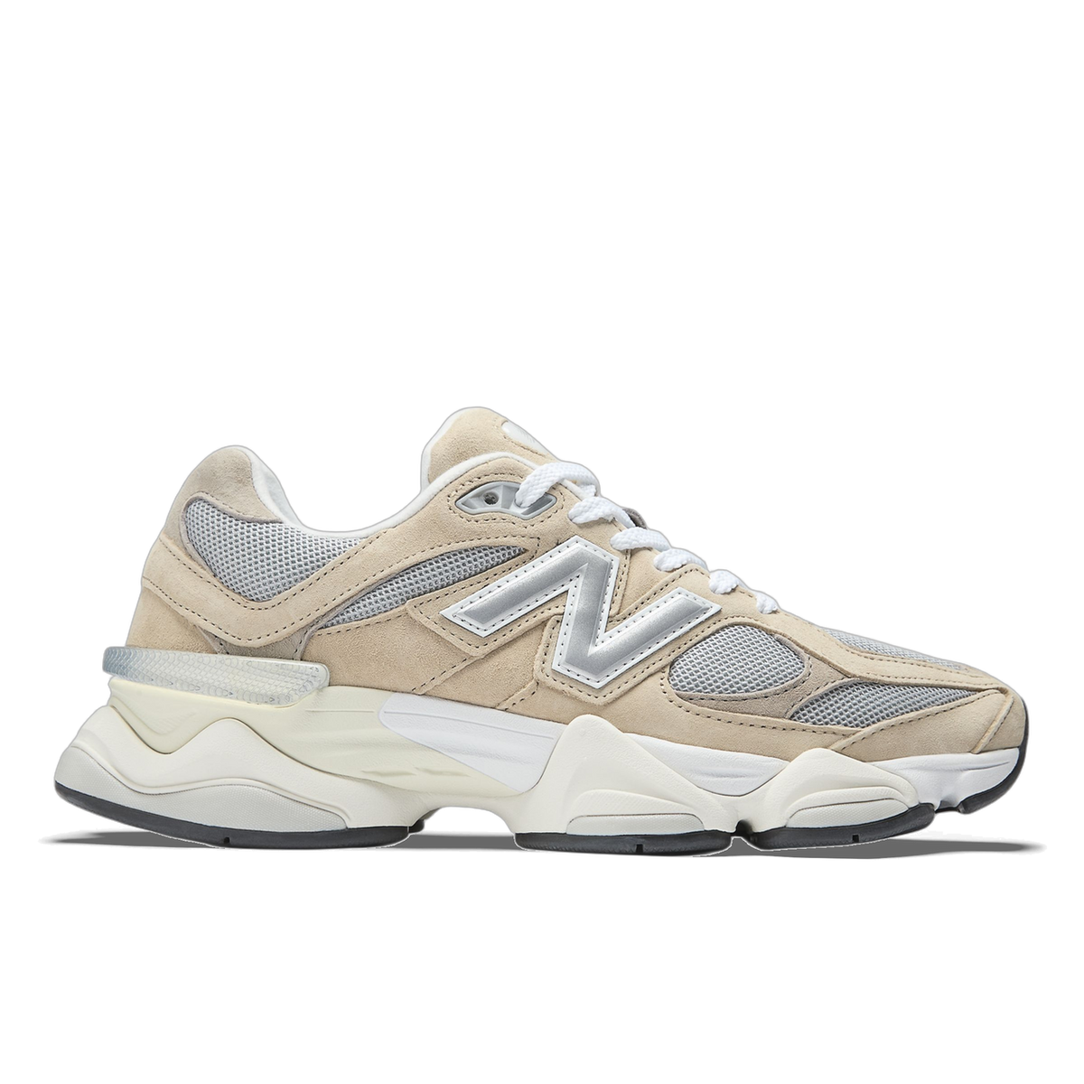 Side view of a beige New Balance 9060 sneaker with silver N logo, mesh panels, and a chunky white and cream midsole, toe pointing left.