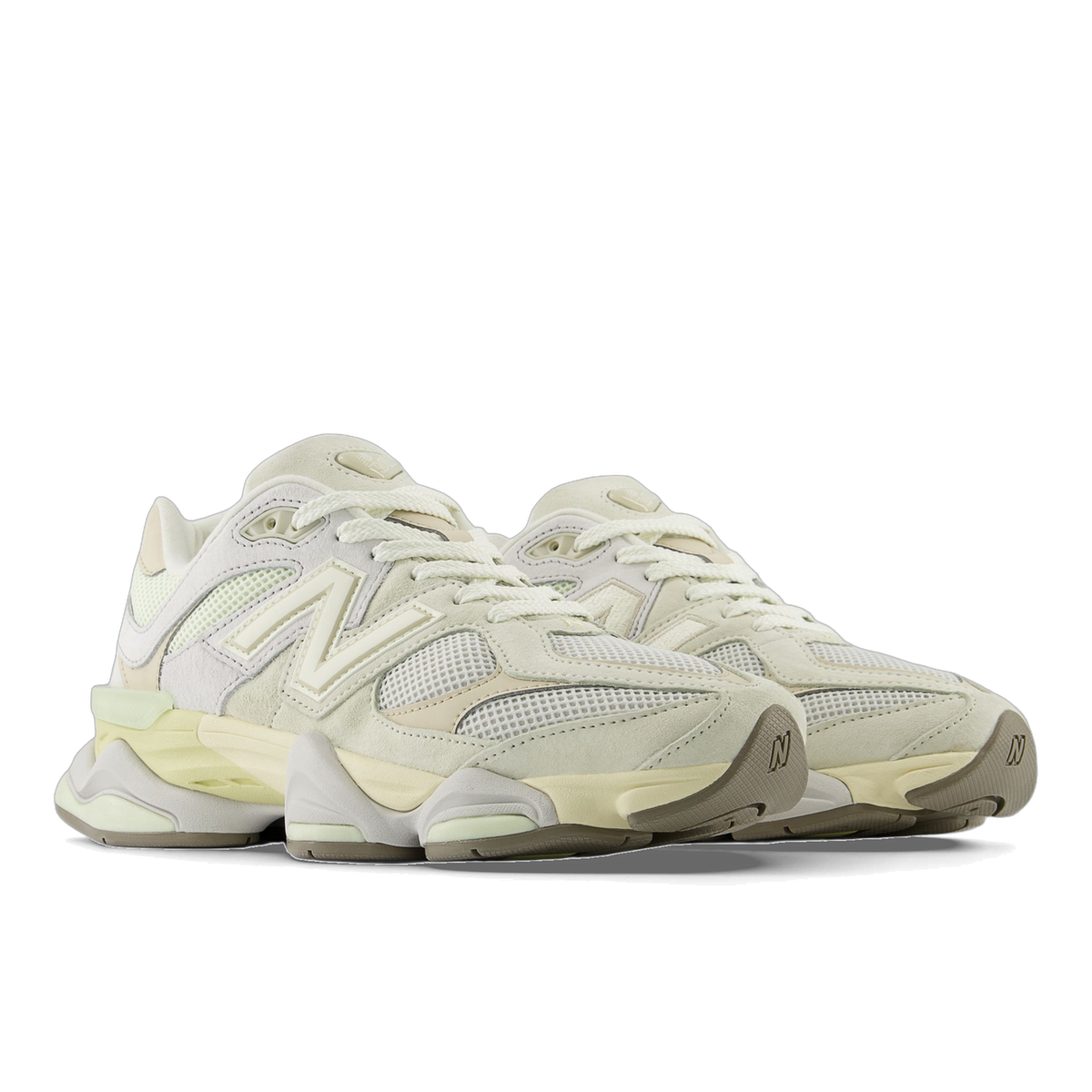 Pair of New Balance 9060 sneakers in off-white and cream tones with mesh panels, suede overlays, and chunky layered soles, shown angled toward the front-left.