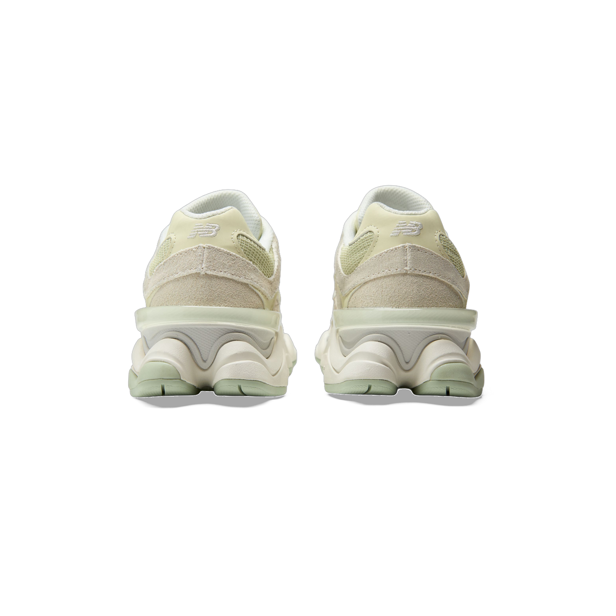 Rear view of a pair of New Balance 9060 sneakers in beige and pale green with white embroidered N logos on the heels.