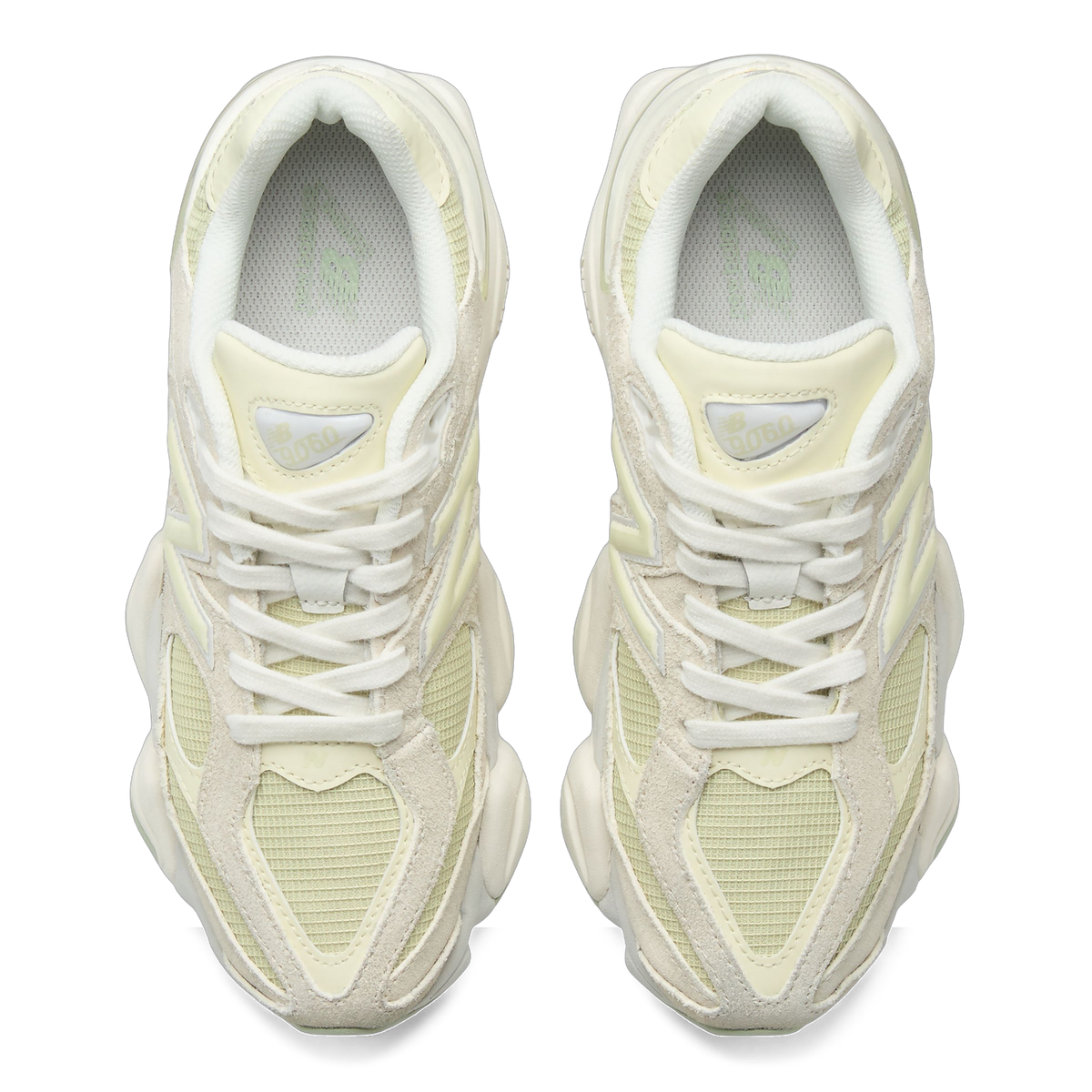 Top-down view of a pair of pale green and cream New Balance 9060 sneakers with white laces and mesh tongues showing the 9060 logo