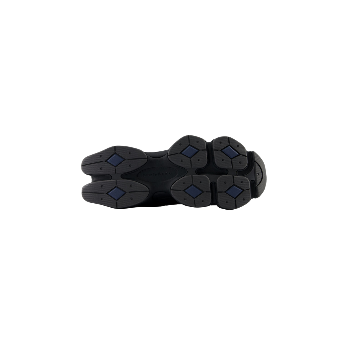 Bottom view of a New Balance 9060 sneaker showing a black outsole with a segmented tread pattern and navy diamond-shaped grip pads.