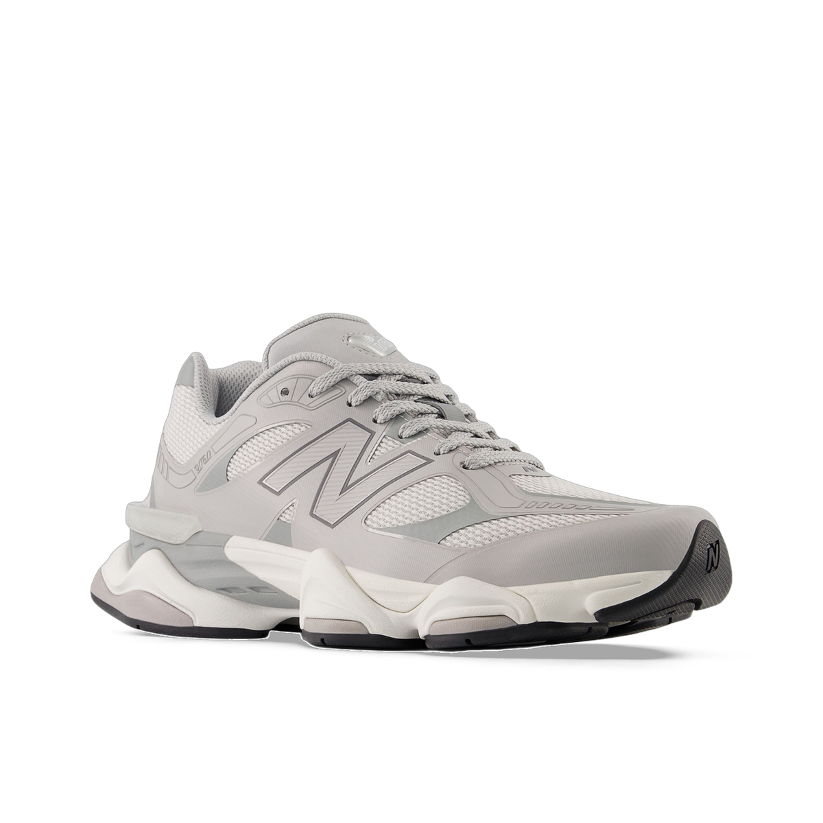 Angled side view of a gray New Balance 9060 sneaker with layered mesh upper, silver N logo, and a chunky white and gray midsole with black outsole accents.