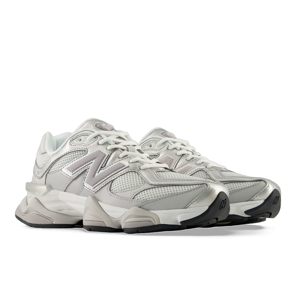 Pair of gray and white New Balance 9060 sneakers with mesh panels shown at a front angle, displaying the N logo and chunky midsole.
