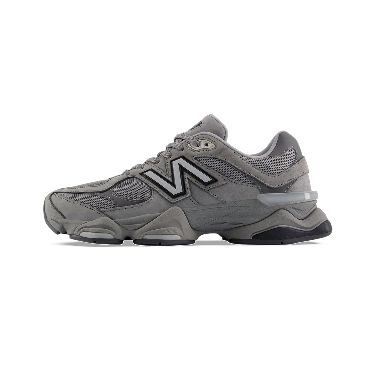 Side view of a grey New Balance 9060 sneaker with a white N logo, mesh paneling, and a chunky sole with visible gel heel insert.