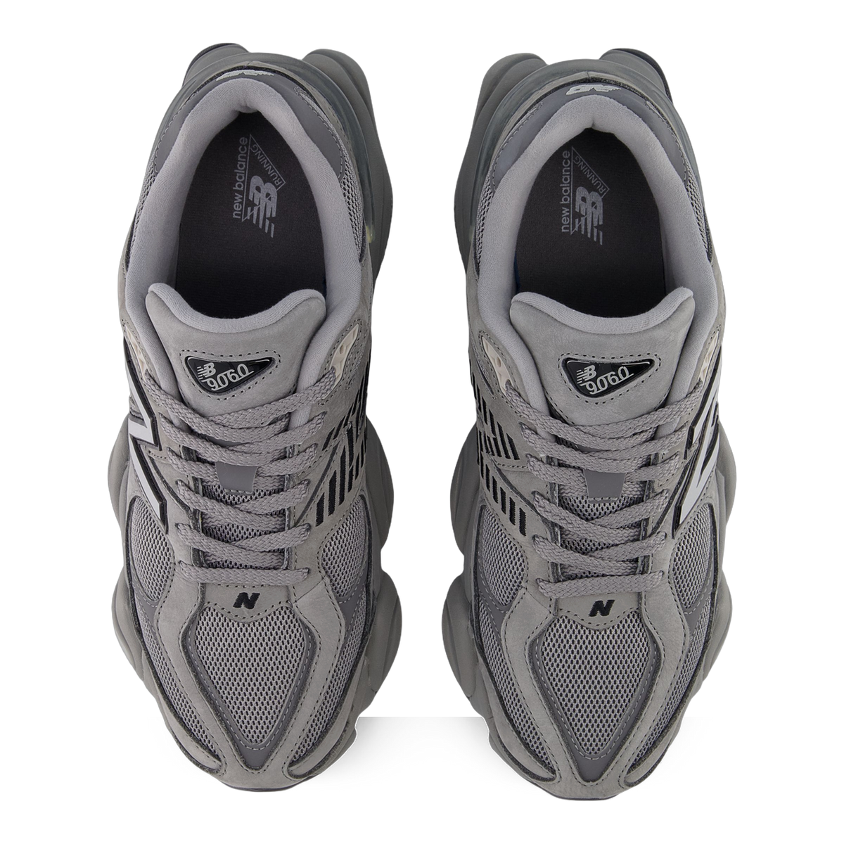 Top-down view of a pair of grey New Balance 9060 sneakers showing laced mesh and suede uppers with visible N logos and 9060 tongue tags.