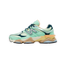 Side view of a mint green New Balance 9060 sneaker with navy heel accents, tan midsole, and silver N logo, toe pointing left.