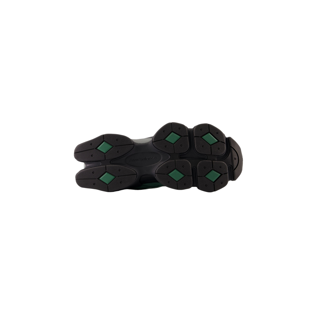 Bottom view of a New Balance 9060 sneaker showing a black outsole with green diamond-shaped traction pods and the New Balance logo molded into the center.