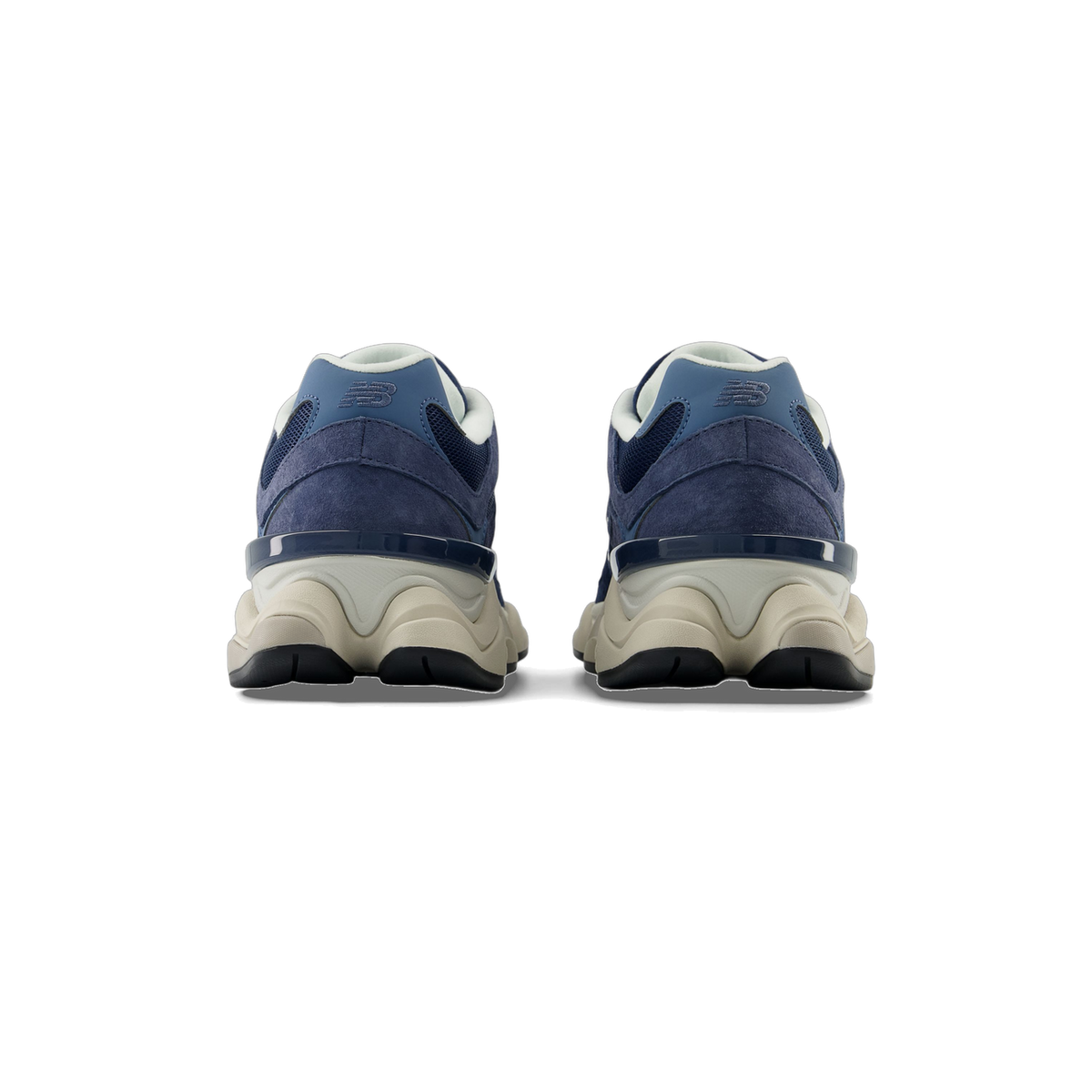 Rear view of a pair of navy blue New Balance 9060 sneakers with suede uppers, embroidered NB logos, and chunky off-white midsoles.