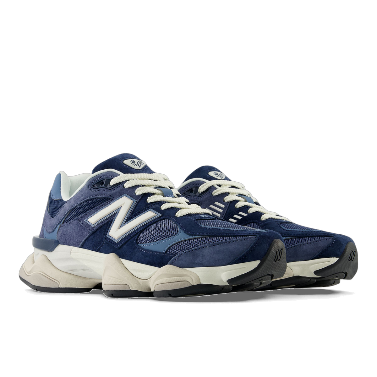 Pair of navy and blue New Balance 9060 sneakers with off-white laces and sole, angled toward the left showing the side logo