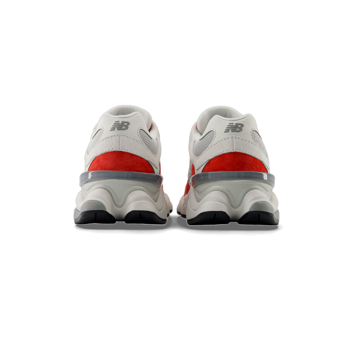 Rear view of a pair of white New Balance 9060 sneakers with red heel panels and grey embroidered NB logos above a chunky midsole and black outsole