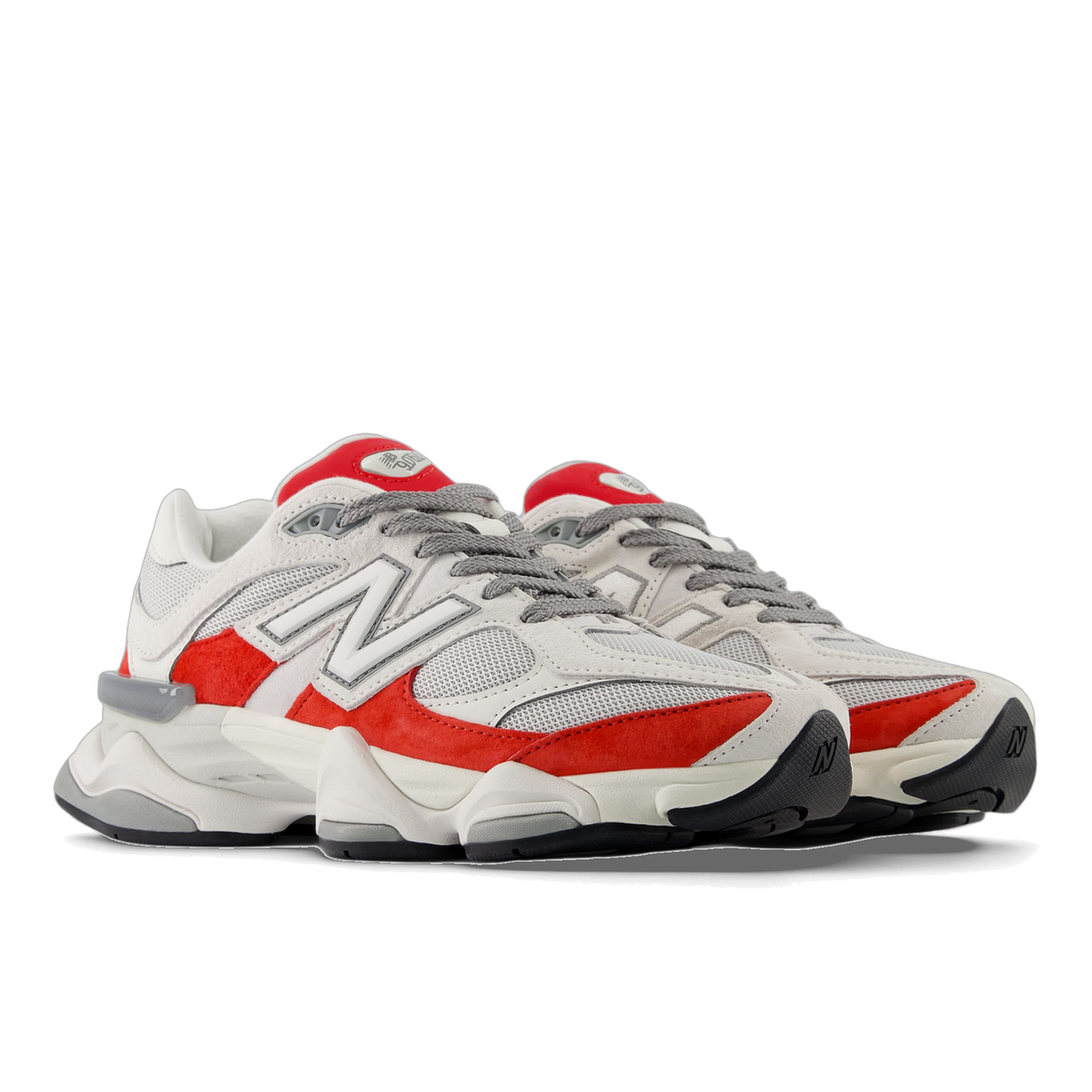 Pair of white and red New Balance 9060 sneakers with grey laces, shown at an angle with toes pointing left.