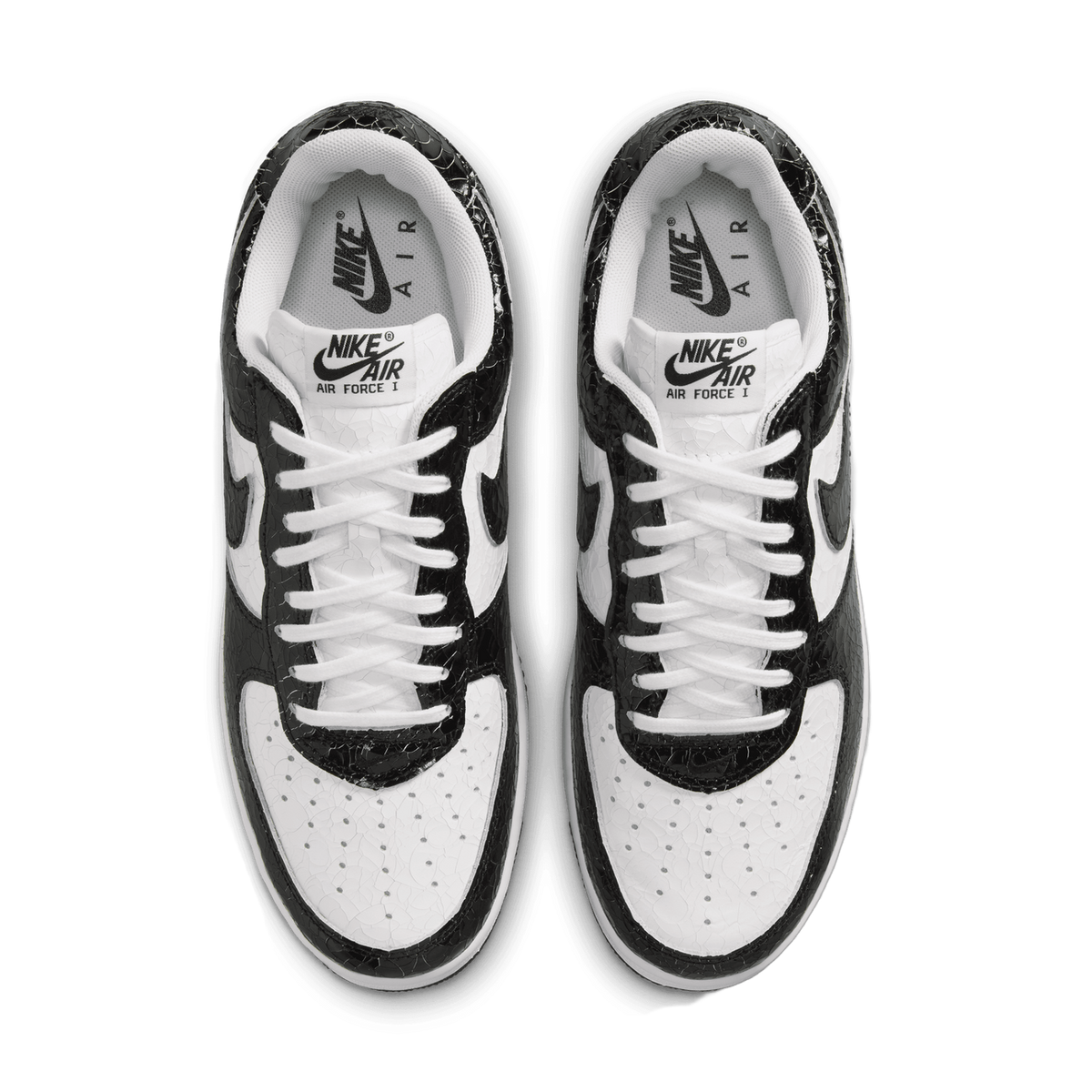 Top-down view of a pair of black and white Nike Air Force 1 Low sneakers with cracked leather texture, showing white laces and tongues labeled Nike Air Force I