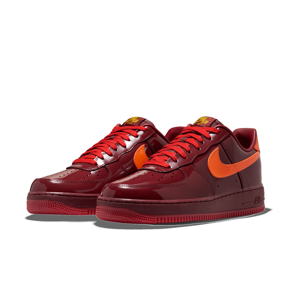 Pair of dark red patent leather Nike Air Force 1 Low sneakers with orange swoosh logos and red laces, angled toward the left