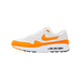 Side view of a white and orange Nike Air Max 1 '86 OG Golf sneaker with toe pointing left, showing the orange swoosh logo and visible Air cushioning in the sole.