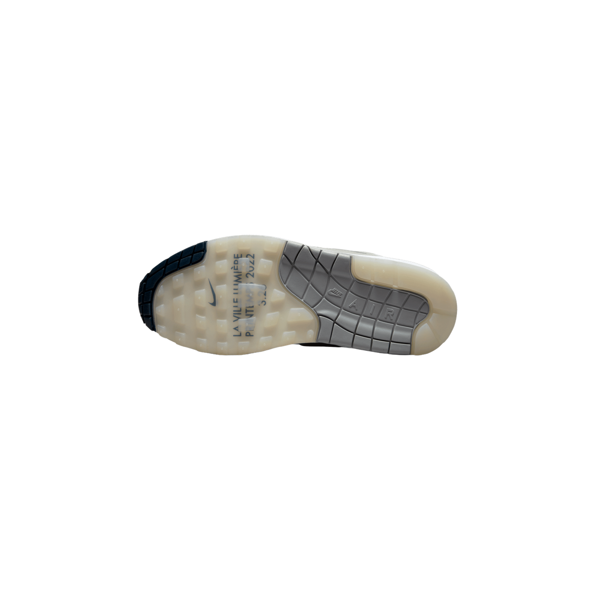 Bottom view of a Nike Air Max 1 AMD showing the cream and grey waffle-patterned outsole with navy heel section and 'La Ville Lumière Printemps 2022' text printed near the arch.