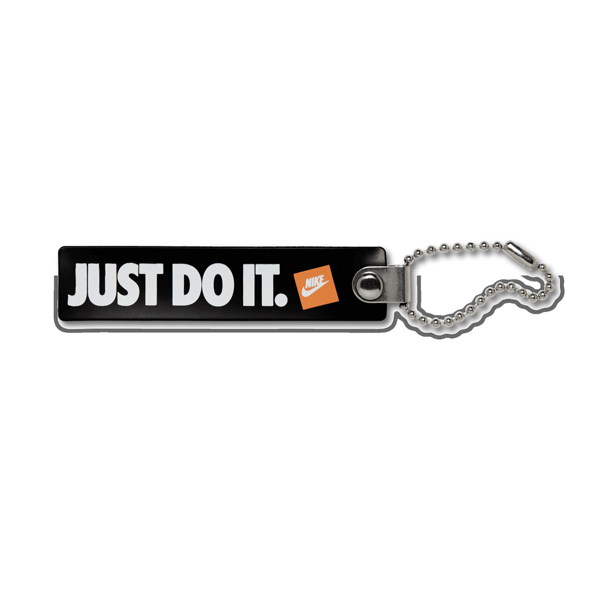 A black rectangular Nike keychain tag reading "JUST DO IT." in white letters with a small orange square Nike Swoosh logo, attached to a silver ball chain on a white background.